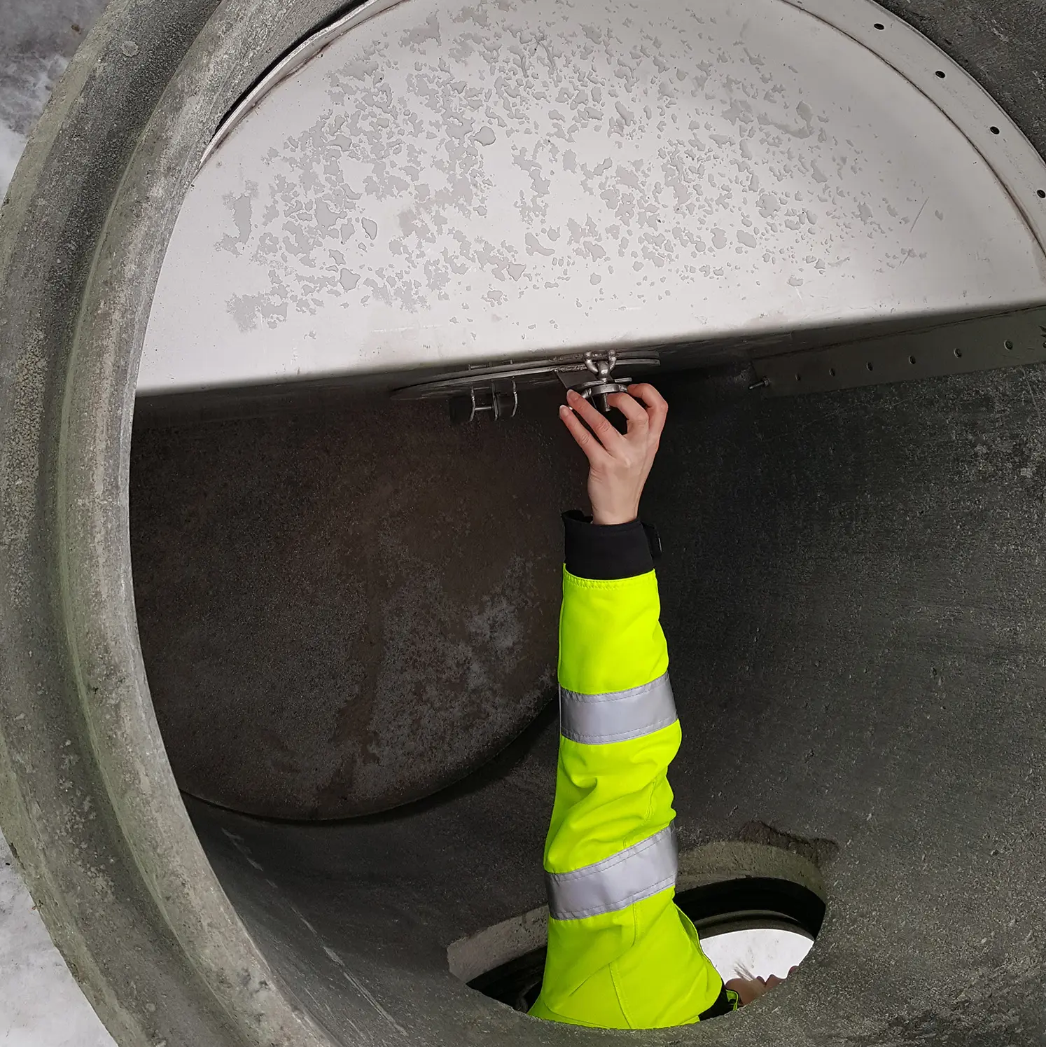 Käsi avaamassa pakkaskaivon huoltoluukkua kunnossapitoa varten